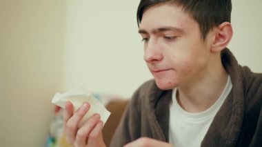 Bornoz giyen adam ev yapımı sandviç yiyor. Erkek, taze ekmekten büyük bir ısırık alıyor. Adam içeride yemek yemeyi seviyor.