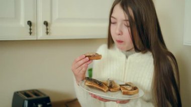 Yemek yerken elinde balık sandviçi olan bir kız. Deniz ürünleriyle kaplı kızarmış tosttan ısırık alan bir kadın. Bayan konserve balıkla ev yapımı atıştırmayı seviyor. Çocuk taze ekmek tadıyor.