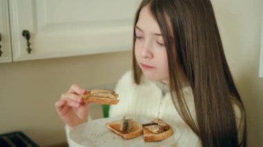Yemek yerken elinde balık sandviçi olan bir kız. Isırılmadan önce dişilerin tostlarını incelemesi. Sıcak mutfakta ev yapımı deniz ürünleri atıştırmayı seven bir bayan. Çocuk çıtır ekmeğin tadını çıkarıyor