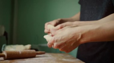 Un kaplı yüzeyde hamuru hamur köftesine çeviren eller. Parmaklar nazikçe bastırıp hamuru katlayarak dolguyu kapatıyor. Mükemmel ev yapımı hamur köfteleri için odaklanmış hamur hazırlığı