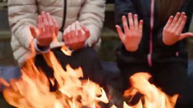 Kardeş ve kardeş, titreyen ateşin üzerinde ellerini ısıtıyor, serin bir akşamda sıcağın tadını çıkarıyor. Hatırlanmaya değer aile anları birlikte geçirilen kış aktiviteleri. Kız ve oğlan dans eden alevlerin yanında avuç içi tutuyorlar.