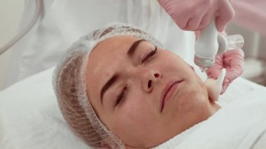 Güzellik uzmanı kadın cilt bakım kliniğinde su temizleme sistemi kullanıyor. Hasta yüz derisini yüzme prosedüründen geçiyor. Tedavi, ölü deri hücrelerini ve safsızlıkları nazikçe ortadan kaldırmaya yardımcı olur