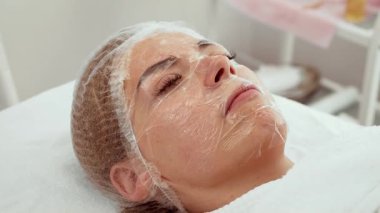 Kadın müşteri özel tedavi sırasında dinleniyor. Hasta derin hidrasyon tedavisi görüyor. Kozmetik dermatoloji kliniği gelişmiş cilt bakımı öneriyor