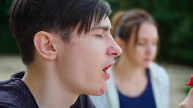 Annesiyle birlikte sulu, olgun kırmızı çilekler yiyen çocuk faydalı vitaminler alıyor. Erkek çocuklu bir kadın açık hava yemeği sırasında tatlı taze kırmızı böğürtlen yiyor, sağlıklı besinleri emiyor. Yemek yiyen çocukla bir kadın.