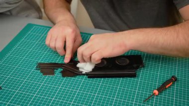 Baba oğul dizüstü bilgisayarın soğutma sistemindeki tozu temizliyor, pamukla bileşenleri siliyor. Erkek temizleme lavabosu ve çocuklu vantilatörler eksiksiz bakım sağlıyor. Oğlanla çalışan adam onarmak için