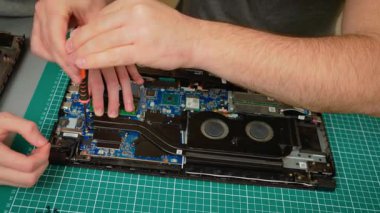 Oğlu ve babası dizüstü bilgisayarı tamir ediyor, soğutma sistemindeki vidaları güvenceye alıyor. Erkek rehber çocuk iç bileşenleri bir araya getirerek düzgün bir işlevsellik sağlıyor. Çocuğa temel adımları öğreten adam: