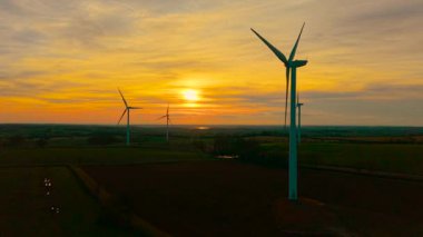 Rüzgar Türbini, Rüzgar Çiftliği Hava Görüntüsü, gün batımında. Rüzgâr türbini, dramatik turuncu gece gökyüzü altında ekolojik enerji sağlamak için rüzgar bıçaklarını döndürür. Dönen hava akımı bıçakları eko enerji üretiyor