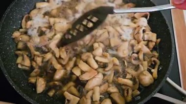 Modern Mutfak 'ta fırında Spatula ile karıştırılırken Kızartma Tavasında Dilimlenmiş Mantar Pişiriyorum. Şef kullanışlı bir spatulayla şampiyonları karıştırır. Lezzetli ve besleyici vejetaryen hazırlamak ya da