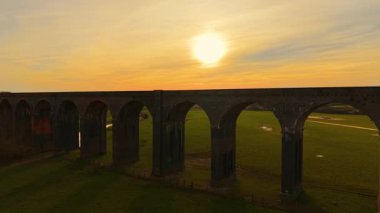 Altın saatte yukarıdan görünen uzak tren köprüsü. Parlak vadiden geçen görkemli viyadük görüntüsü. Ünlü tarihi yerler, ikonik topraklar, ulaşım ağı
