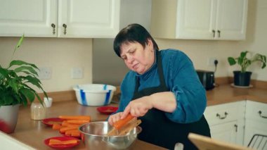 Kadın havuç rendeliyor, mutfakta yemek hazırlıyor. Kadın sebzeleri öğütüyor, içeride yemek yapıyor. Ev yemeklerinde daha büyük, işlem malzemesi kullanan bir kadın.