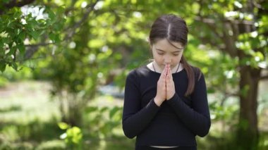 Genç kız Sunny Afternoon sırasında Tranquil Green Park 'ta ciddiyetle namaz kılıyor, Eller Yansıma Anında Birbirine kenetlendi. Dışarıdaki küçük sevimli genç bayan, çocuk ifadesi. Doğadaki çocuklar