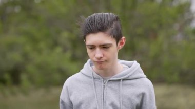 Dışarıdaki üzgün, dalgın genç çocuğun portresi. Melankolik genç adam dışarıda düşüncelere daldı. Açık havada kasvetli bir ifadeyle yansıtıcı ergen çocuk.