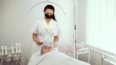 Kozmetik uzmanı estetik merkezindeki işlem sırasında ultrasonik yüz aygıtı kullanıyor. Deri sıkılaştırma ve derin gençleştirme tedavisine odaklanan kadın bir uzman. Bayan Güzellik Uzmanı