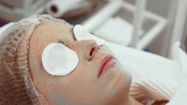 Kadın kozmetoloji stüdyosunda profesyonel yüz maskesi alıyor. Gelişmiş cilt bakımı sırasında kadınlar rahatlar. Müşteri, ışıl ışıl cilt için rahatlatıcı güzellik tedavisinden hoşlanır