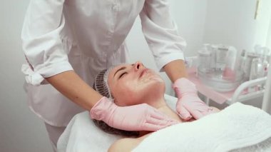 Güzellik terapisti boyun ve yüz masajı yapıyor, hasta rahat. Estetik merkezi profesyoneli, rahatlık sağlamak için nazikçe tedavi ediyor. Cilt bakımı uzmanı müşteri deneyimini kusursuz bir şekilde geliştirir