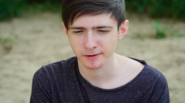 Sarı kivi dilimi yiyen genç bir çocuk düşünceli ve belirsiz bir ifade sergiliyor. Erkek, sarı kivinin tadını çıkararak eşsiz ve keskin lezzetine odaklanıyor. Sarı kivi yiyen adam.