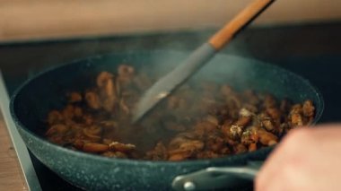 Kızartma tavasında spatula ile karıştırılmış deniz ürünleri karışımı. Zengin soslu midye, karides ve mürekkep balığı karışımı. Kabuklu deniz hayvanlarını cızırdayan tavaya atmak. Kabaran deniz mahsullerinde baharat eşit olarak dağıtılır.