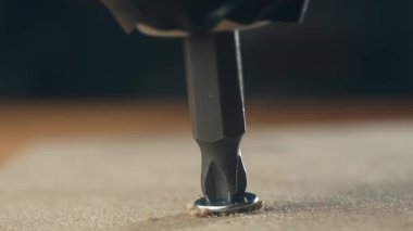 Yakın çekim tornavida vidası battı, tahta yüzeye vida battı. Hırdavat aletleri yavaş yavaş tamir sırasında daha hızlı sürüyordu. İnşaat sahnesinde vidayla çalışan metal parçası
