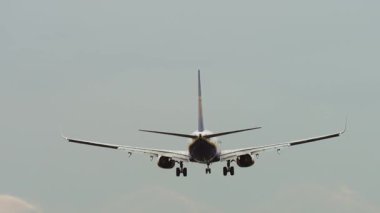 Yolcu uçağı havaalanına iniyor. İniş takımları açık ve ters itiş gücü açık. Bulutlu gökyüzü koşulları altında yakalanan son iniş anı