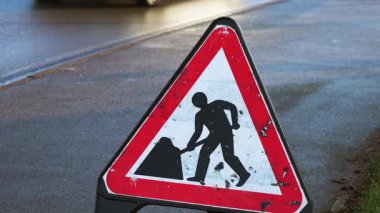 Birleşik Krallık 'ta inşaat uyarı işareti. İleride İngiltere 'de yol çalışması olduğunu gösteren trafik uyarısı panosu. Yol güvenliği işareti İngiltere 'de otoyol bakımını gösteriyor