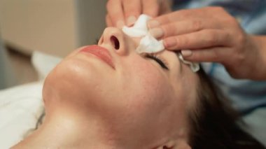 Islak pedlerle profesyonel temizlik yüzü, cilt hazırlama. Yüzünü nemli süngerlerle tedavi etmek, hazırlığı arttırmak. Cilt bakımı uzmanı yüzünü nazikçe siliyor ve hazırlanmasını sağlıyor. Nemli giysilerle terapist yüz temizleme, optimizasyon.