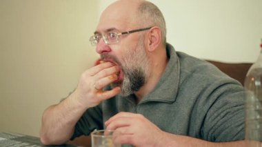 Yemek masasında sosislinin son lokmasını yiyen adam. Erkek, evde peynirli ve arsız atıştırmalıkların tadını çıkarıyor. Adam lezzetli ev yapımı sandviçi bitiriyor. Evdeki dağınık ve tatmin edici yemeğin tadını çıkaran kişi