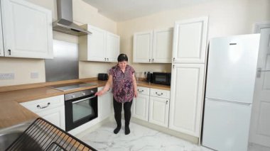 Mutfakta dans eden gülümseyen kadın, hafifçe yan yana yürürken neşeli anın tadını çıkarıyor. Hayat dolu havada hoplayıp zıplayan oyuncu. Neşeli bayan rahat sallanıyor, neşeli hareketlere dalmış.