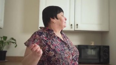 Mutfakta özgürce dans eden neşeli bir kadın. Şen şakrak bir karakter neşe içinde dönüyor. Keyifli bir bayan ev ortamında neşeyle sallanıyor.