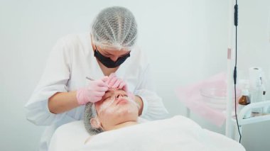 Modern kozmetoloji kliniğinde çalışan bir kadın cilt kusurlarını tedavi ediyor. Gelişmiş dermatolojik aletler kullanarak akne sorunlarını ele alan bir kadın. Profesyonel bakım gören bir kız, doğal cilt sağlığını geliştiriyor.