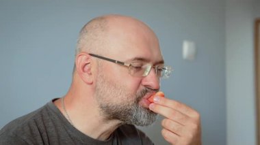 Komik kel adam domates dilimi yiyor. Taze domatesin tadını çıkartan kel bir erkek. Kel adam neşeli yemek anında sulu sebzelerin tadını çıkarıyor.