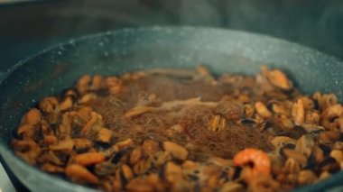 Kabaran sosta deniz ürünleri karışımı kaynıyor. Zengin et suyunda midye, karides ve mürekkep balığı pişirmek. Kaynatılmış kabuklu deniz ürünleri karışımı, kalın ve lezzetli salamura. Yavaş pişmiş deniz ürünleri tabağında derin tatlar emiyor.