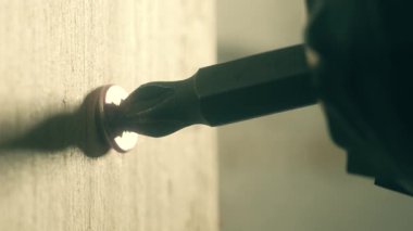 Kapalı sarı kendine dokunan vida duvardan söküyor. Makro görünüm donanım hızlandırıcısı tamirci tarafından yüzeyden çekiliyor. İnşaat sırasında inşaatçı tarafından çalışan pirinç vida