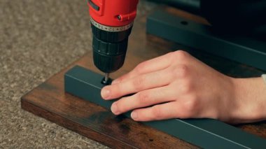 Elektrikli matkap kullanarak, mobilyaları içeride monte ederek. Erkek, tornavidayla tamir ekipmanı. Ev düzenini geliştirmek için donanımla çalışan adam