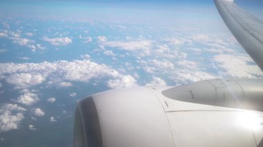 Uçaktan Hava Görüntüsü Gün Işığı Uçuşu sırasında Bulutları ve Motoru Gösteriyordu. Pencerenin yanında türbin ve kanatlar var. Kabarık beyaz bulutların üzerinden geçen uçak