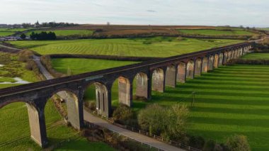 Gün batımında sakin kırlara yayılan yüksek viyadük. Viyadük demiryolunun, yemyeşil vadiden manzaralı geçişi. Ünlü mekanlar, ikonik bölge, çarpıcı doğa vasıtasıyla ulaşım yapısı