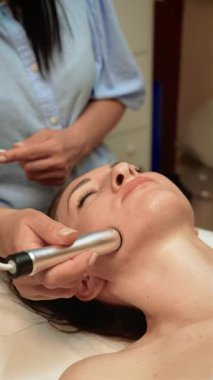 Estetik terapist çene hattında vakum yüz masajı yapıyor, dikey yönelim. Cilt bakımı uzmanı lenfatik drenajı geliştirmek için emme teknolojisi kullanıyor. Gelişmiş Elektroporasyon Cilt Tedavisiyle Güzellik Uzmanı Cilt Rengi