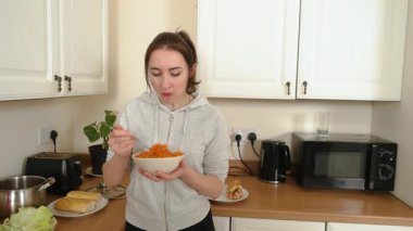 Mutfakta havuç salatası yiyen bir kadın. İçerde parçalanmış sebze tatma tabağı. Lezzetli ev yapımı yemekleri seven bir bayan. Evde taze mezelerin tadını çıkaran biri var.