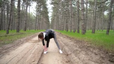 Genç zayıf kadın ormanda egzersiz yapıyor. Genç, narin bir kadın ormanda çalışıyor. Genç bayan ormanda fiziksel egzersiz yapıyor.