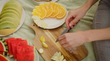 Dilimlenmiş limon ve portakalları tahta tahtanın yanına koyan kadın. Servis veya dekorasyon için narenciye parçaları düzenleyen bir kadın. Bayan sunum için taze narenciye dilimleri hazırlıyor.