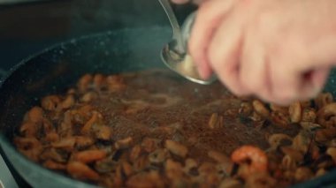 Kaşıktan deniz ürünleri tabağına baharat serpmek. Kaynayan kabuklu deniz ürünlerine kuru baharat karışımı ekliyorum. Köpüren karides ve midyelerin üzerine baharat dök. Aromatik baharatlarla zengin deniz mahsulleri tatlandırmak.
