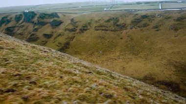 Sisli gökyüzünün altındaki boş dağ asfaltı yolu. İngiltere, Peak District 'teki sakin manzara engebeli tepelerle çevrilidir. Yumuşak sisli ufukta sakin bir atmosfer var. Dönek yolu olan huzurlu kırsal manzara