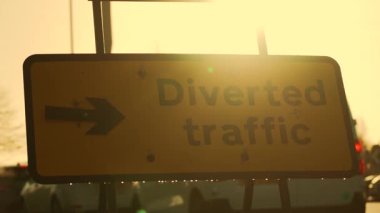 Altın ufukta duran trafik işaretleri. Sabah ışığında sokak tabelası figürü. Yol sapağı parlayan gündoğumu atmosferinde karanlık bir şekil olarak görünüyor