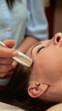 Cilt bakımı profesyonel olarak tapınakta Darsonval Tedavi uyguluyor, dikey yönelim. Kan dolaşımını iyileştirmek için yüksek frekanslı elektroterapi kullanan estetik uzmanı. Güzellik terapisti gelişmiş Darsonval Cilt ile cilt yenilenmesini arttırıyor