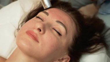 Müşteri, sağlık merkezindeki profesyonel masözün canlandırıcı yüz masajı deneyimi yaşıyor. Donanım Yaşlanma Karşıtı Tedavi, Mikroakım Yüz Yenileme. Yüz tazeleme, cilt bakımı, olgun kadınlar için yaş sınırı aşma yöntemi, güzellik uzmanı.