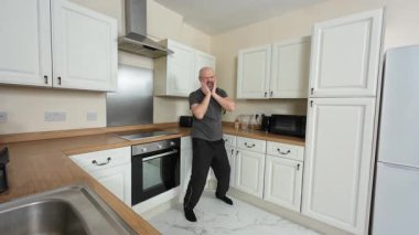 Hevesli bir adam mutfakta dans ediyor ve şarkı söylüyor. Duygularını müzikle ifade ederken neşeyle hareket ediyor. Zevkle dans ederek kıvranan özgür ruhlu biri. Heyecanlı birey ritmik olarak sallanıyor, tamamen neşeli bir performansa dalmış.