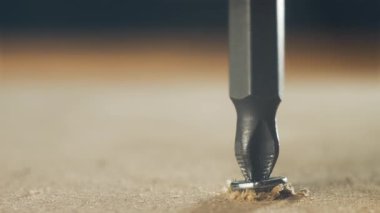 Yakın çekim tornavida vidası battı, tahta yüzeye vida battı. Tamir sırasında metal bağlayıcıyı sıkan donanım aleti. Yavaş yavaş inşaat işinde çalışıyorum.