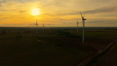 Gün batımında hava manzaralı güzel rüzgar türbini. Rüzgar türbini güçlü bıçakları hareket ettiriyor dramatik turuncu gece gökyüzü altında çevre dostu güç sağlamak için. Hareket eden pervaneler rüzgar çiftliğinde yenilenebilir enerji üretiyor
