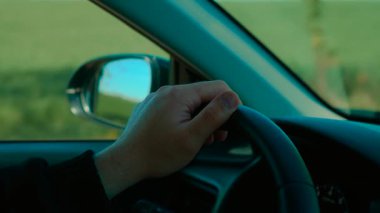 Yeşil alanın yanından geçen tanınmayan bir adam el ele tutuşup direksiyona geçiyor. Erkek direksiyon aracı, kırsal yolda kontrolü sağlıyor. Sürücü sakince yol alıyor, direksiyonu tutuyor manzaralı yolda.