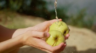 Akan suyun altında yeşil elmaları yıkamak. Çocuk taze elmaları suyla temizlerken duruluyor. Elma tutan ve dışarıda yıkayan bir genç.