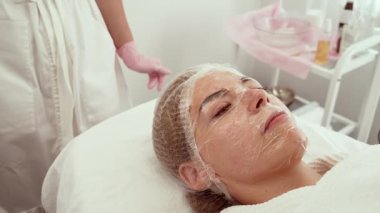 Kadın kozmetoloji kliniğinde yüz gerdirme ameliyatı sırasında sakince yalan söylüyor. Profesyonel tedavi, yüz hatlarını ve deri esnekliğini geliştirmeye odaklanıyor. Gelişmiş kozmetik bakım altında dinlenen müşteri yenilenmeyi ve sıkılaşmayı hedefliyor.